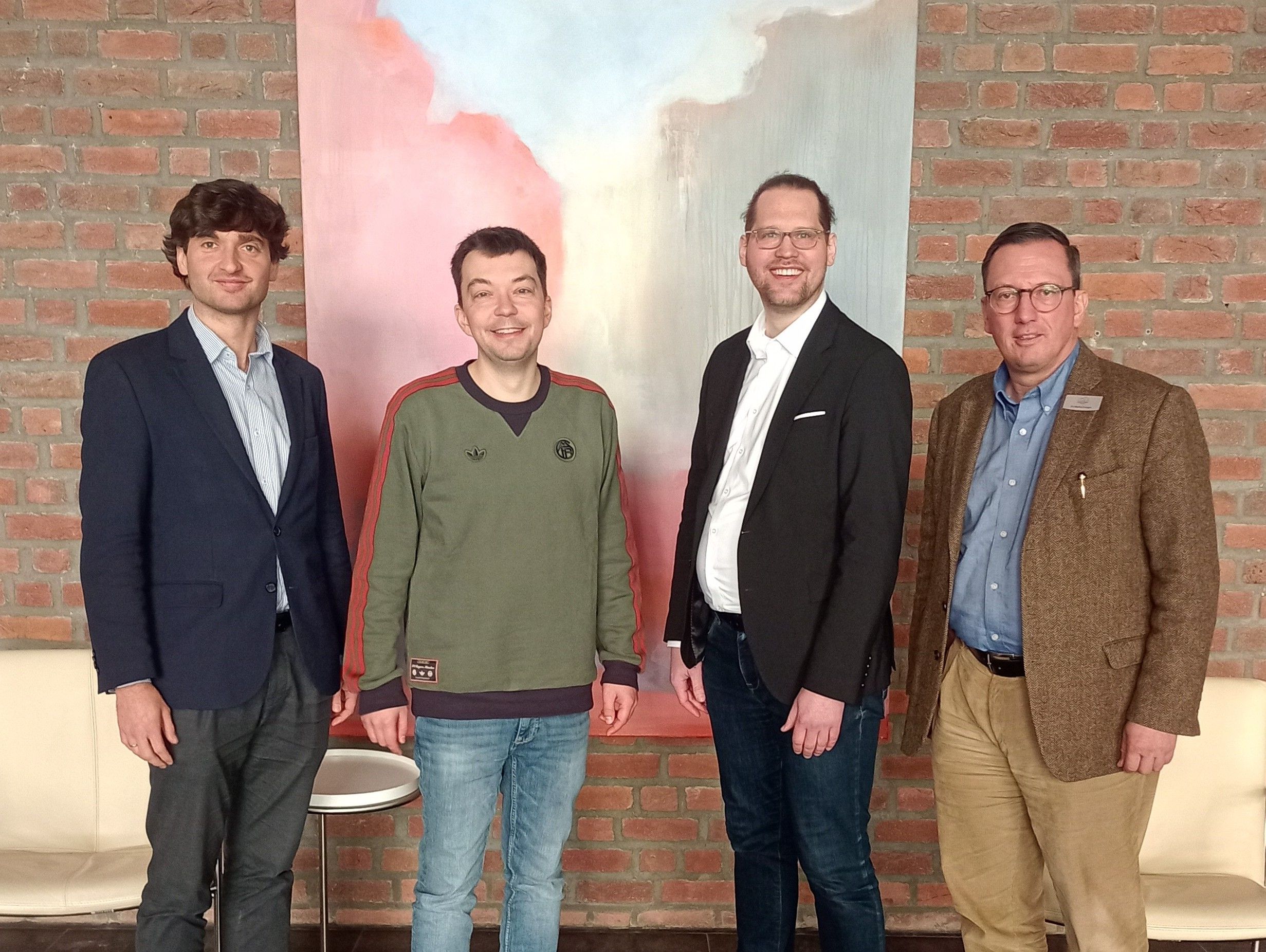 Vier Personen stehen vor einem Bild.